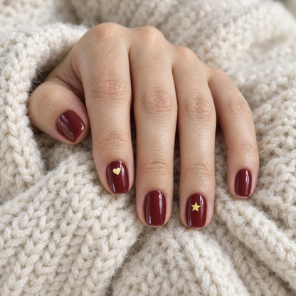 Burgundy manicure with a tiny yellow heart and star that look like nail art